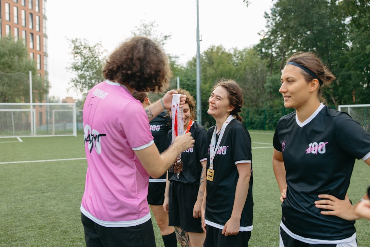 A womens football team receiving medals on the field, celebrating their victory.